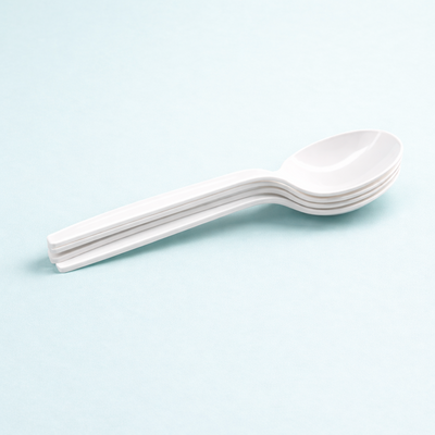Stack of white disposable plastic spoons on a light blue background